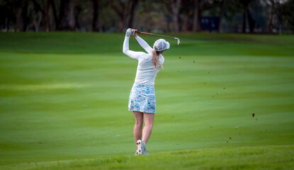 Professional woman golfer teeing golf in golf tournament competition at golf course for winner