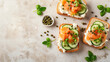 Open faced smoked salmon sandwiches with fresh herbs and cream cheese on rustic background