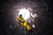 © ivan - Rope access specialist in a cooling tower. A worker inspects the building