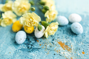 Canvas Print - Yellow beautiful flowers and blue and yellow colored easter eggs on a blue picturesque oil painting background close up. Mockups. Layout. Spring pastel background. Easter pastel contemporary backgroun