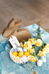 Poster - Yellow beautiful flowers and blue, yellow colored easter eggs in wicker basket, and easter bunny on a blue picturesque oil painting background close up. spring Mockups.Layout. Easter pastel background