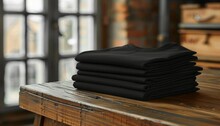 stack of folded black tshirt or tees on wood table