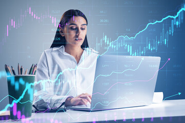 Poster - Attractive young businesswoman using laptop at desk with creative glowing candlestick forex chart on blurry background. Financial trade and market concept. Double exposure.