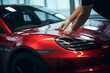 © Yuliia - Professional unrecognizable Caucasian specialist male man guy worker master wrapping installing protective film vinyl foil new red sport car automobile transport paint protection indoors salon service