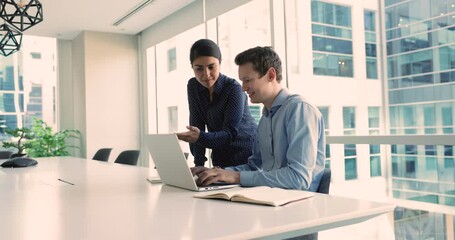 Canvas Print - Two multi-ethnic teammates working on joint task, solve business issues, corresponding to client by e-mailing at meeting in city office boardroom. Modern tech usage, workflow, teamwork, cooperation