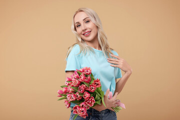 Wall Mural - Happy young woman with beautiful bouquet on beige background