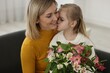 © New Africa - Little daughter kissing and congratulating her mom with bouquet of alstroemeria flowers at home. Happy Mother's Day