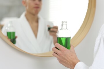 Canvas Print - Young man using mouthwash near mirror in bathroom, closeup