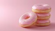 © tashechka - Stack of pink frosted donuts with colorful sprinkles on a pink background, sugary treat.