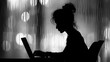 A silhouette of woman typing on a laptop