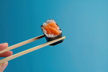 Wall Mural - A person holding chopsticks with a piece of sushi in between them