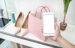 hand with smarthone against shopping bag and shoes,business and e-commerce concept image,copy space for text