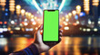 hand holds a smartphone with green screen against defocused night street lights,business,internet,online communication,concept image,copy space for text