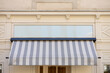 Gray and white awning over the windows on the white wall
