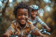 Young boy with a big smile riding his bicycle in a park with a blurred friend in the background