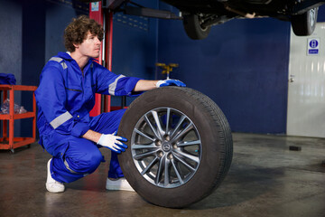 Wall Mural - mechanic holding and pushing a tire for fixing in garage