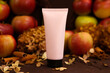 cosmetic moisturizing cream in pink tube bottle with black screw cap, apples, cinnamon, dried flowers. Body cream, gel, skincare, shampoo, hair conditioner or packaging mockup in autumn composition.