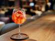 Transparent pink alcohol cocktail in wine glass with ice, aperol and gin on bar counter in restaurant interior. Alcohol drink Aperol Spritz aperitif cocktail. Cold alcoholic cocktail in bar or