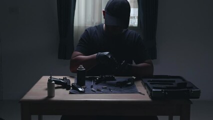 Wall Mural - Slow motion image of a man sitting alone in a room. He would disassemble and clean a 9 mm semi-automatic pistol. assembling the gun. military ammunition. weapon care.