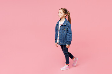 Full body side view little child smiling cute kid girl 7-8 years old wears denim shirt have fun walking go isolated on plain pastel light pink background. Mother's Day love family lifestyle concept