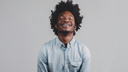 Sticker - cheerful man with curly hair, smiling at the camera, arms crossed, wearing a light blue casual shirt, standing against a light gray background.