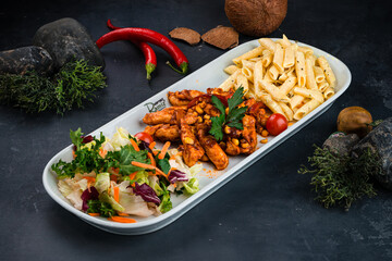 Canvas Print - Penne pasta with chicken, sweet pepper, corn, sauce and fresh vegetable salad of carrots, lettuce, cabbage and tomatoes.