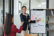 Young professional young asian businesswoman confidently presenting charts and graphs during a corporate meeting.