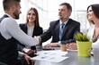 © opolja - Happy businessmen shaking hands at group board meeting. Professional business executive leaders making handshake agreement successful company trade partnership