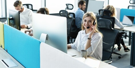 Wall Mural - Female customer support operator with headset and smiling.