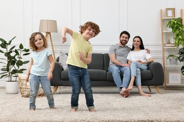 Wall Mural - Happy children dancing while their parents looking at them in room