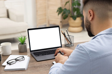 Sticker - E-learning. Young man using laptop at wooden table indoors, closeup