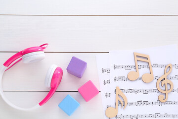 Wall Mural - Notes, music sheets, headphones and cubes on white wooden table, flat lay with space for text. Baby song concept