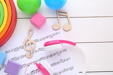 Wall Mural - Notes, music sheet, headphones and toys on white wooden table, flat lay with space for text. Baby song concept