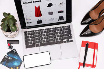 Canvas Print - Online store website on laptop screen. Computer, smartphone, stationery, credit cards, women's shoes and lipstick on white background, above view