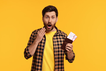 Wall Mural - Surprised man with passport and tickets on yellow background