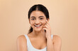 © Prostock-studio - Cheerful indian woman in white top touching her face with gentle smile