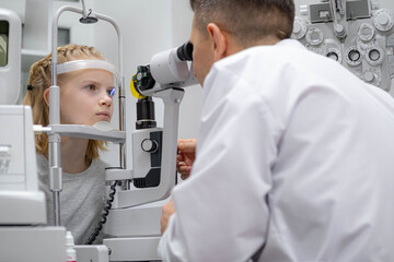 Wall Mural - doctor and young patient in eye clinic, girl undergoing an eye test with professional optometrist using advanced diagnostic equipment, pediatric ophthalmology examination