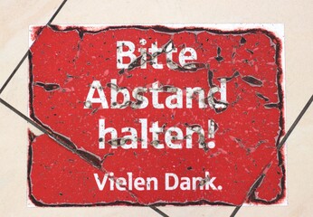 Wall Mural - Worn-out red sign on tiled floor in German: Bitte Abstand halten, Vielen Dank. Translated to: Please keep distance. Thank you very much. Concept: worn-out warning signs, social distancing signs.