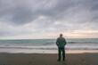 © CesareFerrari - Solitary man standing by the seaside and staring in the distance. He's wearing a military outfit and is not recognizable.