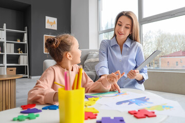 Wall Mural - Female psychologist working with little girl drawing at table in office