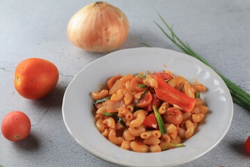 Wall Mural - Macaroni in tomato sauce with fresh tomato and onion in white plate. Top view, horizontal composition. Popular italian food.