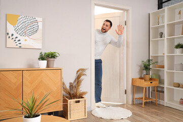 Wall Mural - Happy young man peeking out door in living room