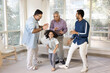 © fizkes - Happy Indian men of three family generations and little kid dancing at home together, celebrating family event. Girl having fun, enjoying motion, activity with dad, granddad and great grandpa