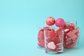 Canvas Print - Tasty pink candies in glass jars on light blue background, space for text