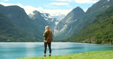 Lake, mountain or woman hiking in nature adventure to explore outdoors for holiday vacation. Tourist thinking, walking or back of hiker trekking in Norway for travel, exercise or journey for view