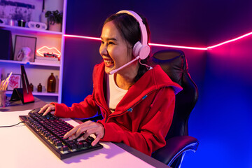 Host channel of smiling beautiful Asian girl streamer playing online game wearing headphone talking with viewers media online recording phone. Esport skilled team players in neon blue room. Stratagem.