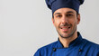 An image of a man cooking in a blue chef's costume with a sincere smile on his face set on a snow-white background