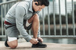 © Charnchai saeheng - A man tying shoelaces on sport shoes in the city center park before cardio workout, running.  Health and Lifestyle in big city life concept.