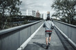 © Charnchai saeheng - A man running up on footbridge in the city center park for cardio workout.  Health and Lifestyle in big city life concept.