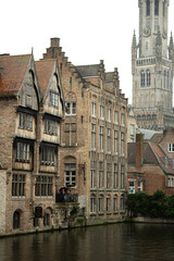 Wall Mural - Bruges in Belgium. Historic houses in the city center with a church in the background.